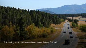 Peak to Peak Scenic Byway in Colorado surrounded by evergreen forest and changing yellow and gold aspen trees in fall.